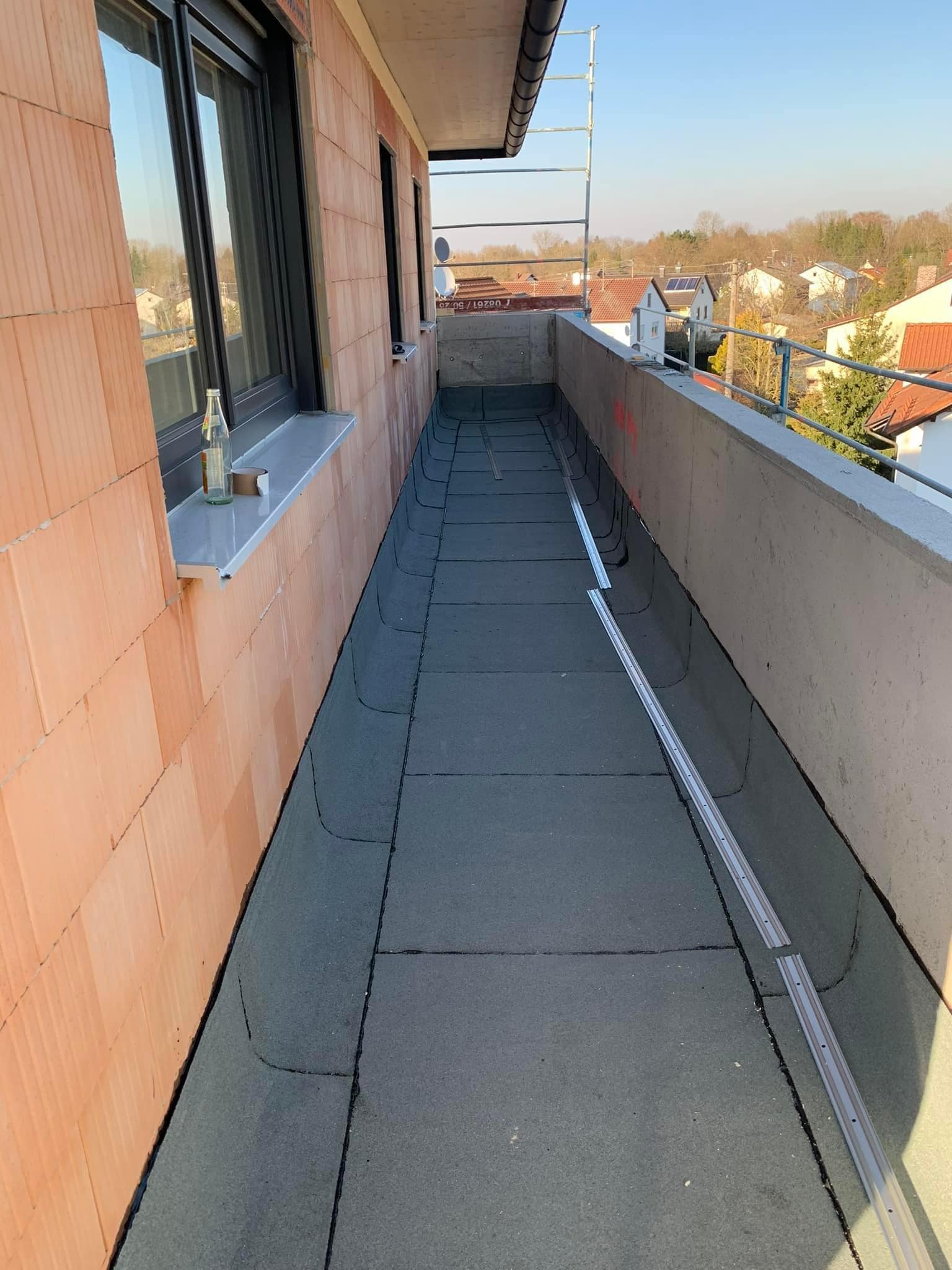 Schmaler Dachstreifen mit Bitumenabdichtung entlang einer Fassade